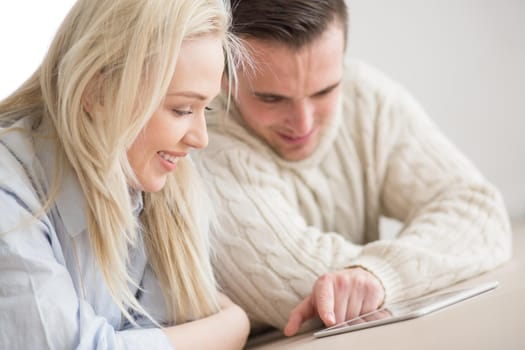 Young Couple on the floor in front of fireplace surfing internet using digital tablet on cold winter day