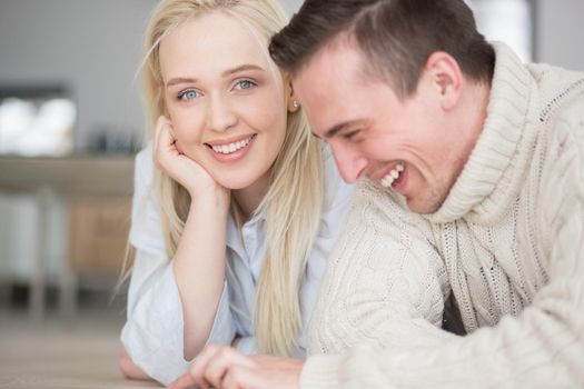 Young Couple on the floor in front of fireplace surfing internet using digital tablet on cold winter day