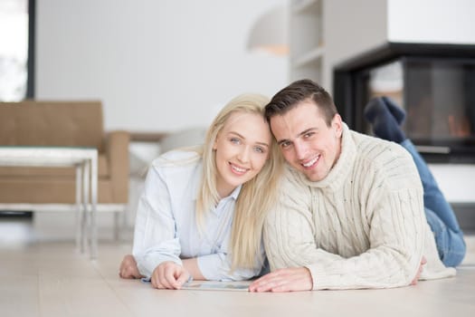 Young Couple on the floor in front of fireplace surfing internet using digital tablet on cold winter day