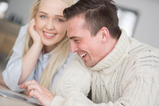 Young Couple on the floor in front of fireplace surfing internet using digital tablet on cold winter day