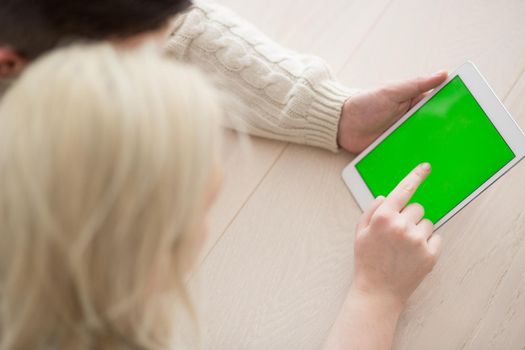 Young Couple on the floor in front of fireplace surfing internet using digital tablet on cold winter day