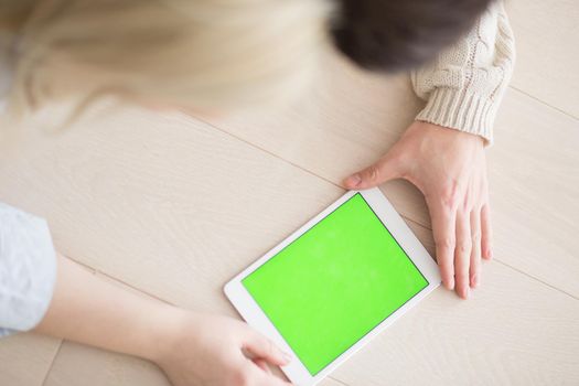 Young Couple on the floor in front of fireplace surfing internet using digital tablet on cold winter day