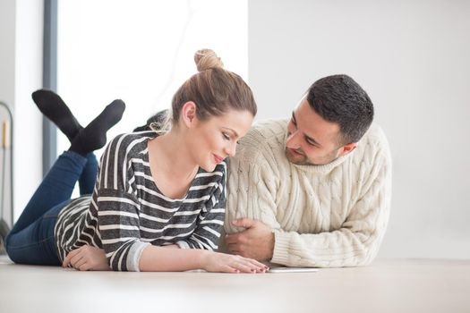 Young Couple on the floor in front of fireplace surfing internet using digital tablet on cold winter day