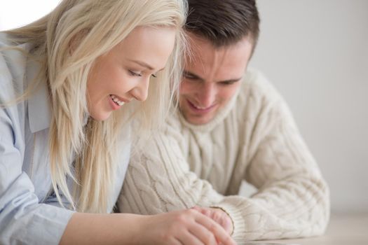 Young Couple on the floor in front of fireplace surfing internet using digital tablet on cold winter day