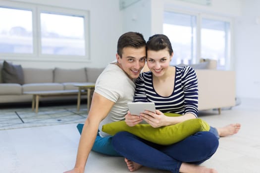 Young Couple sitting on the floor and using interent on digital tablet