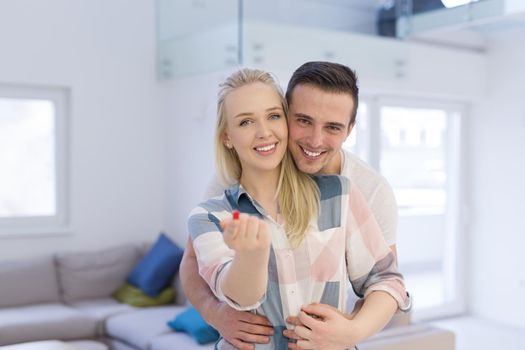 Happy couple hugging and showing small red house in hands Concept of buying house to start a family
