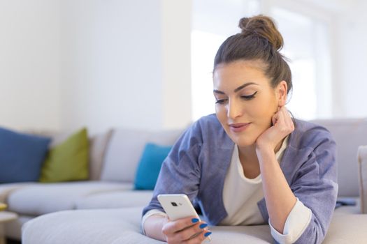 young happy woman using mobile phone on sofa at luxury home