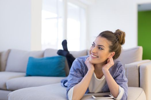 young happy woman using mobile phone on sofa at luxury home