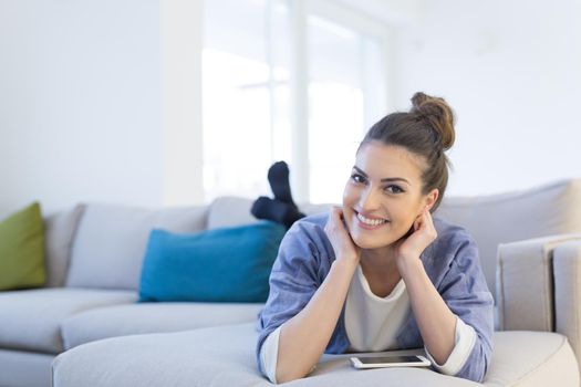 young happy woman using mobile phone on sofa at luxury home