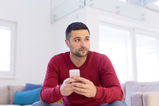 Handsome casual young man using a mobile phone at  home