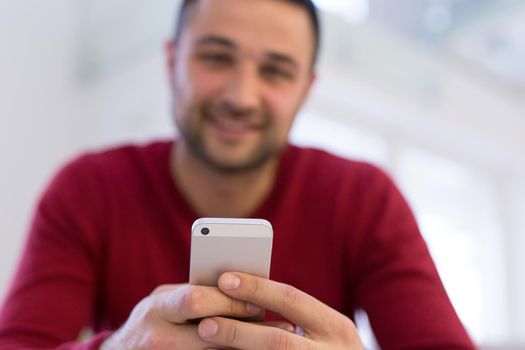 Handsome casual young man using a mobile phone at  home