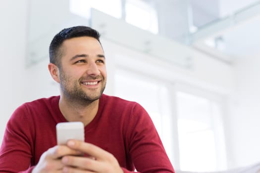 Handsome casual young man using a mobile phone at  home