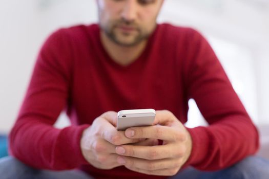 Handsome casual young man using a mobile phone at  home