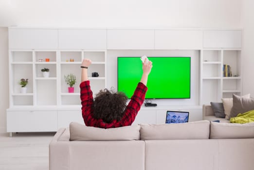 young handsome man in bathrobe enjoying free time watching television in his luxury home