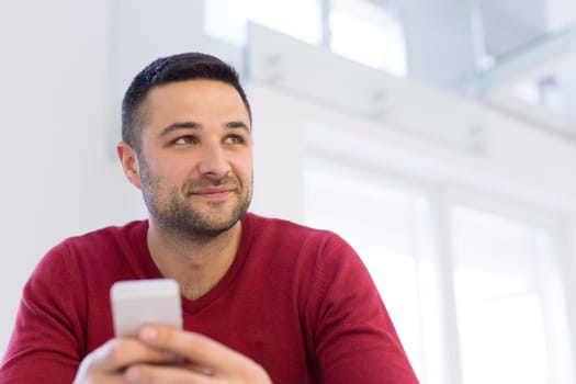 Handsome casual young man using a mobile phone at  home