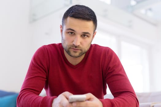 Handsome casual young man using a mobile phone at  home