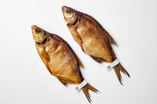 Top view of two salty smoked breams with paper labels on tails isolated on white background with copyspace. Popular fish snack concept