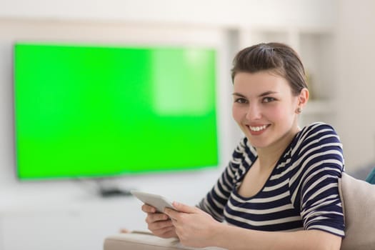 young happy woman on sofa using tablet computer at luxury home