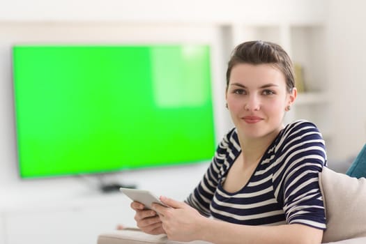 young happy woman on sofa using tablet computer at luxury home