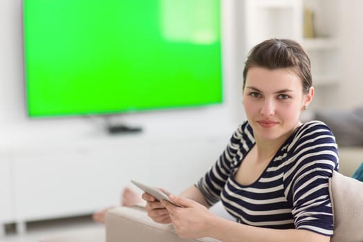 young happy woman on sofa using tablet computer at luxury home