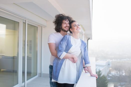 Couple in love sharing emotions and happiness while hugging on the balcony at home