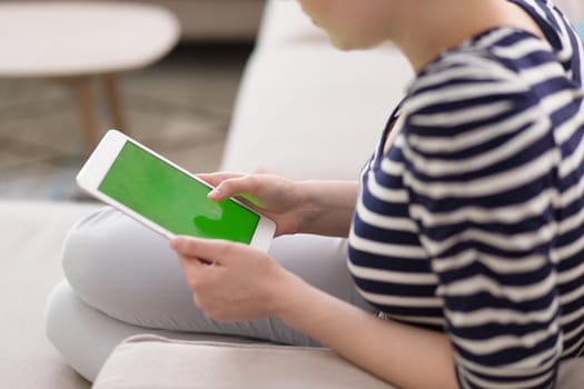 young happy woman on sofa using tablet computer at luxury home