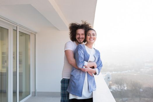 Couple in love sharing emotions and happiness while hugging on the balcony at home