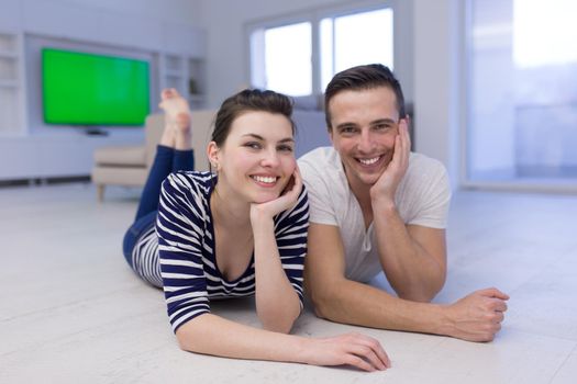 Lovely couple enjoying free time lying on the floor in their living room at home