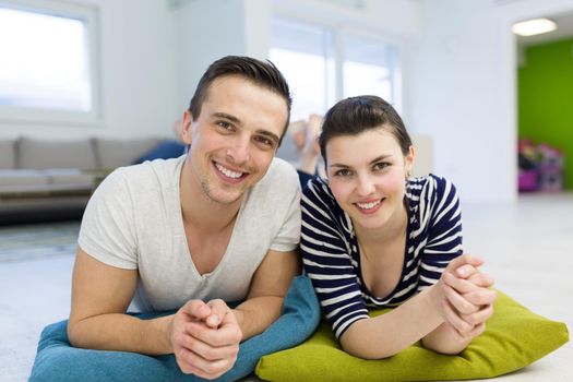 Lovely couple enjoying free time lying on the floor in their living room at home