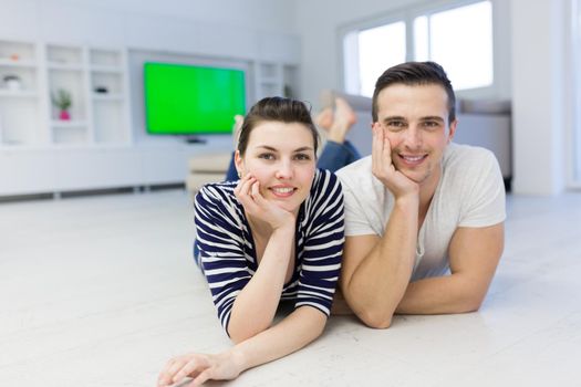 Lovely couple enjoying free time lying on the floor in their living room at home