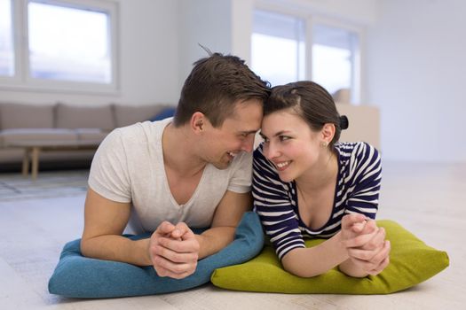 Lovely couple enjoying free time lying on the floor in their living room at home