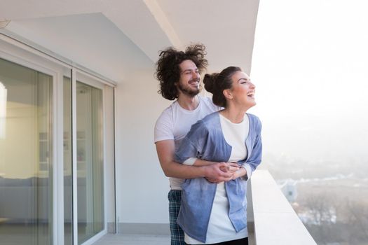 Couple in love sharing emotions and happiness while hugging on the balcony at home