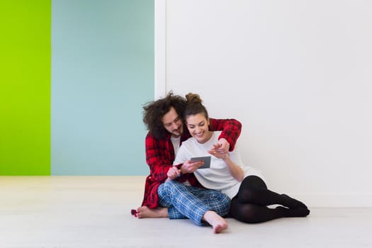 Young Couple sitting on the floor and using interent on digital tablet