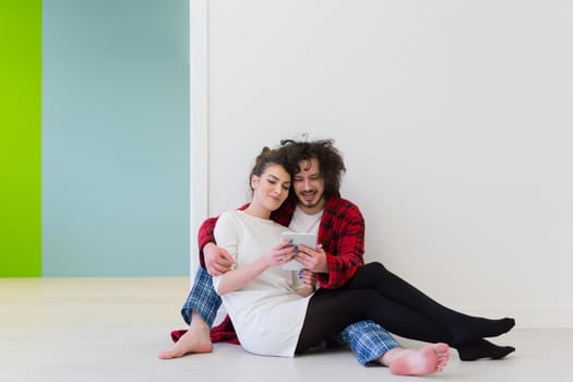 Young Couple sitting on the floor and using interent on digital tablet