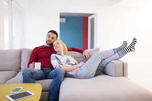 Happy young couple hugging and relaxing on sofa at home