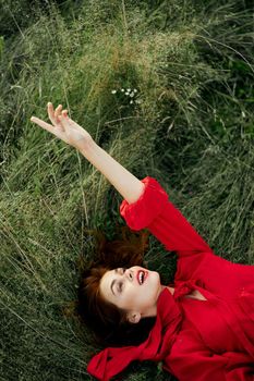 woman in red dress lies on the grass fresh air nature freedom. High quality photo