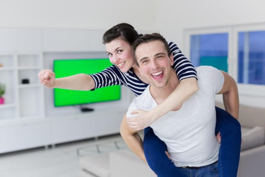 happy young man piggybacking his girlfriend at home