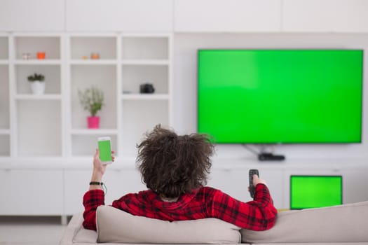 young handsome man in bathrobe enjoying free time watching television in his luxury home