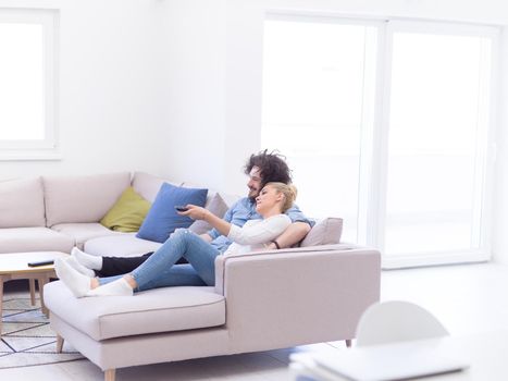 Young couple on the sofa watching television together in their luxury home