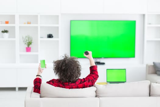 young handsome man in bathrobe enjoying free time watching television in his luxury home