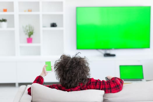 young handsome man in bathrobe enjoying free time watching television in his luxury home