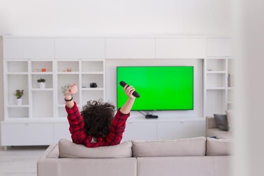 young handsome man in bathrobe enjoying free time watching television in his luxury home