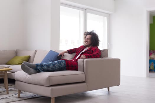 young handsome man in bathrobe enjoying free time watching television in his luxury home