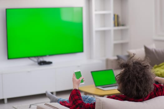 young handsome man in bathrobe enjoying free time watching television in his luxury home