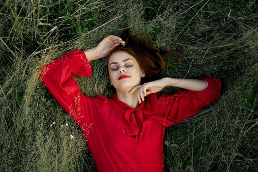 woman in red dress lies on the grass nature freedom summer. High quality photo