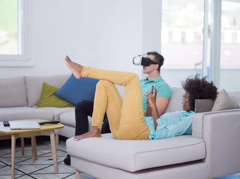 Multiethnic Couple using virtual reality headset in living room at home  people playing game with new trends technology