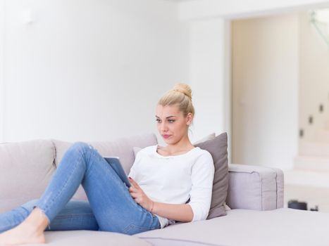 young happy woman on sofa using tablet computer at luxury home