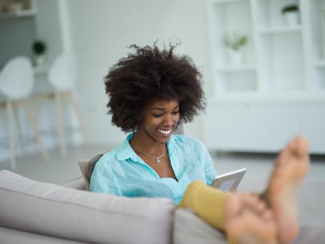 Young african american woman at home relaxing in her luxury lliving room reading a digital tablet  surf internet and work