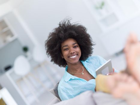 Young african american woman at home relaxing in her luxury lliving room reading a digital tablet  surf internet and work