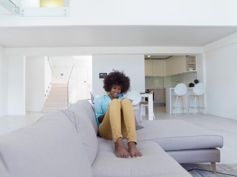 Young african american woman at home relaxing in her luxury lliving room reading a digital tablet  surf internet and work